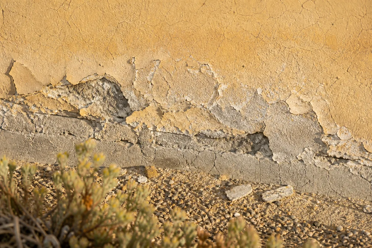 Enduit clair cloqué et écaillé sur le pied de mur d’une villa du littoral