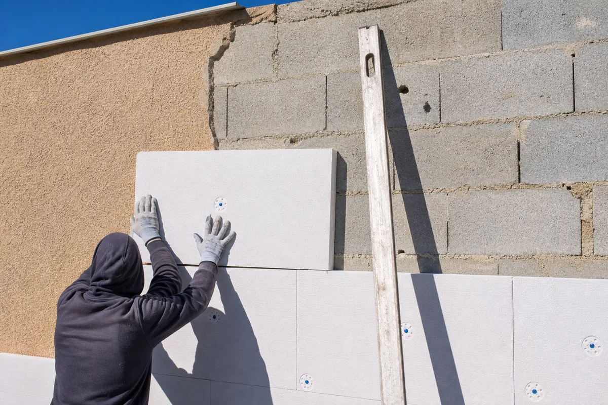 Façade de villa méditerranéenne en cours d’isolation par l’extérieur, panneaux isolants posés sur la moitié du mur